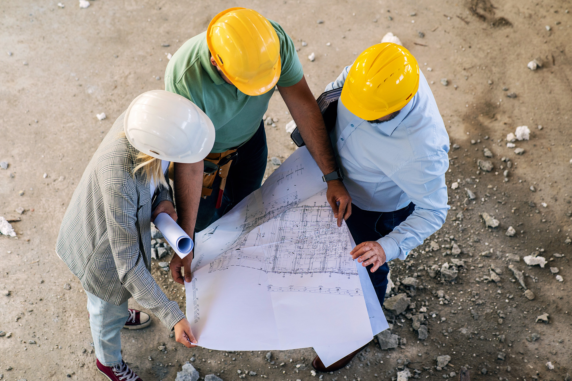 A group of architects work together on-site, discussing blueprints and coordinating to bring their project to life.