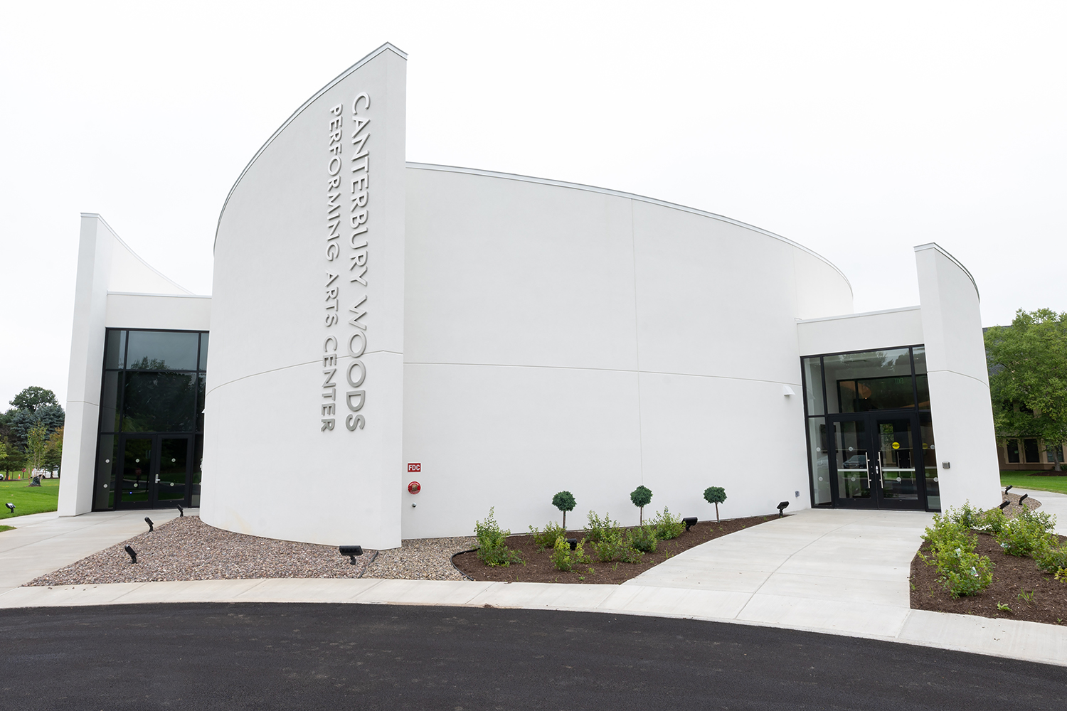 Closeup of white building with curved walls and an entrance on each side with “Canterbury Performing Arts Center” on the front