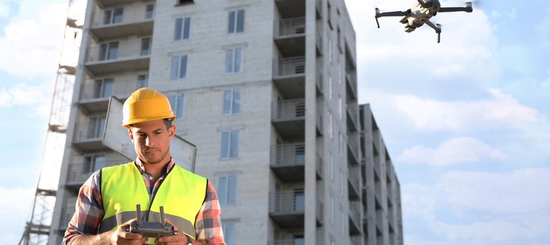 Builder operating drone with remote control at construction site. Aerial photography